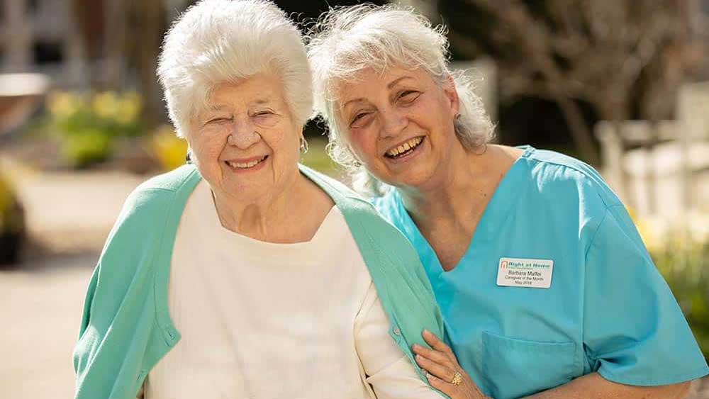 smiliing-senior-and-caregiver-outdoors