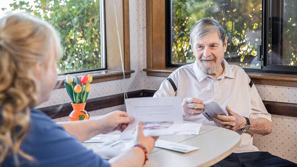 senior man reviewing documents with caregiver
