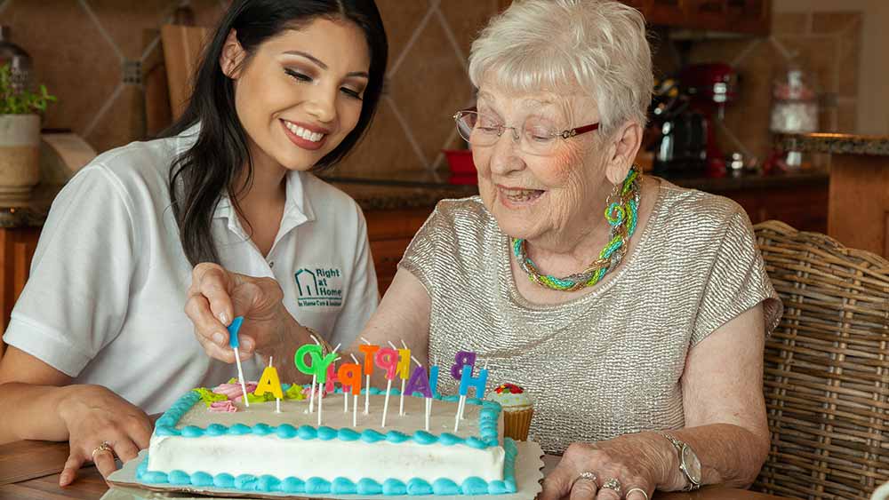 senior and caregiver celebrating birthday with cake
