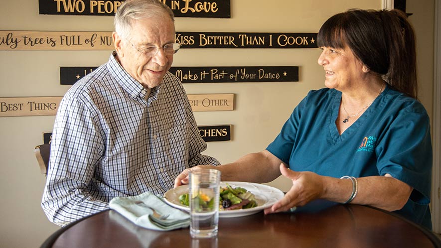 caregiving-serving-senior-at-table