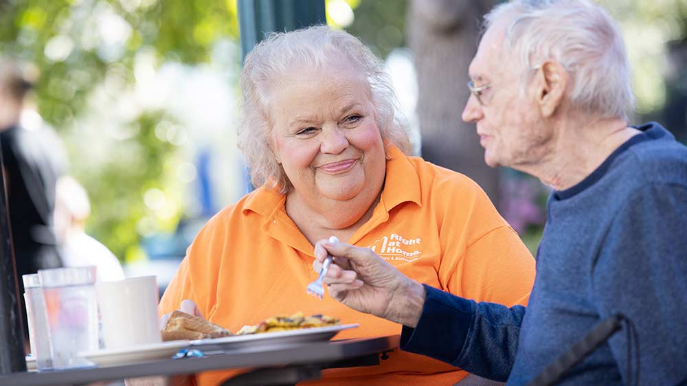 senior-eating-with-caregiver-at-table