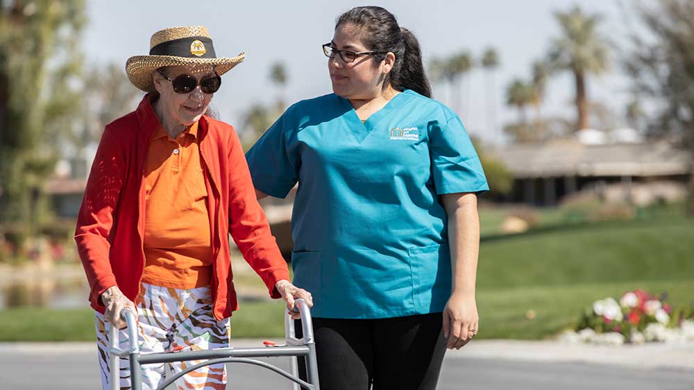 senior-woman-with-walker-assisted-by-female-caregiver