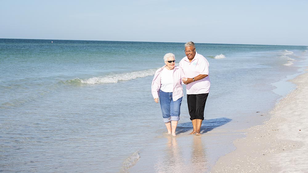 caregiving-assisting-female-senior-with-walk-on-beach