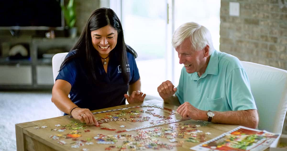 caregiver and senior putting together a puzzle