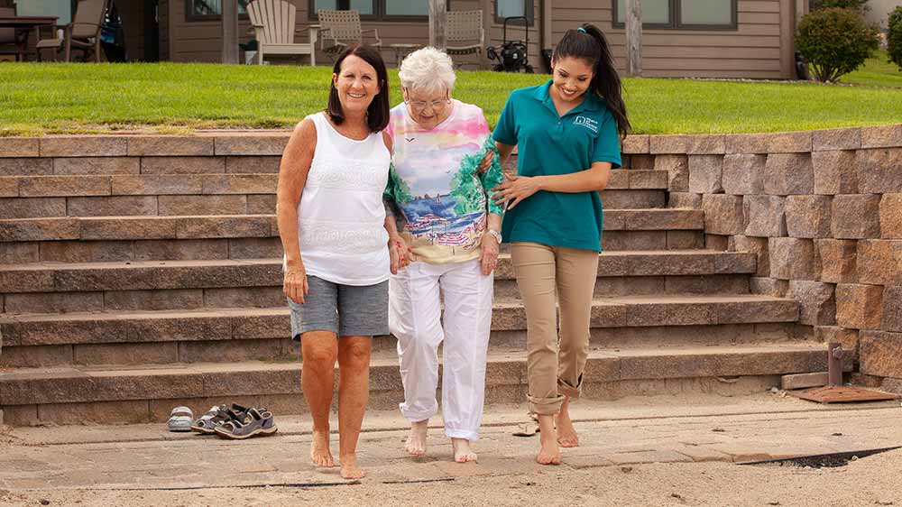 family caregiver and caregiver walking with senior