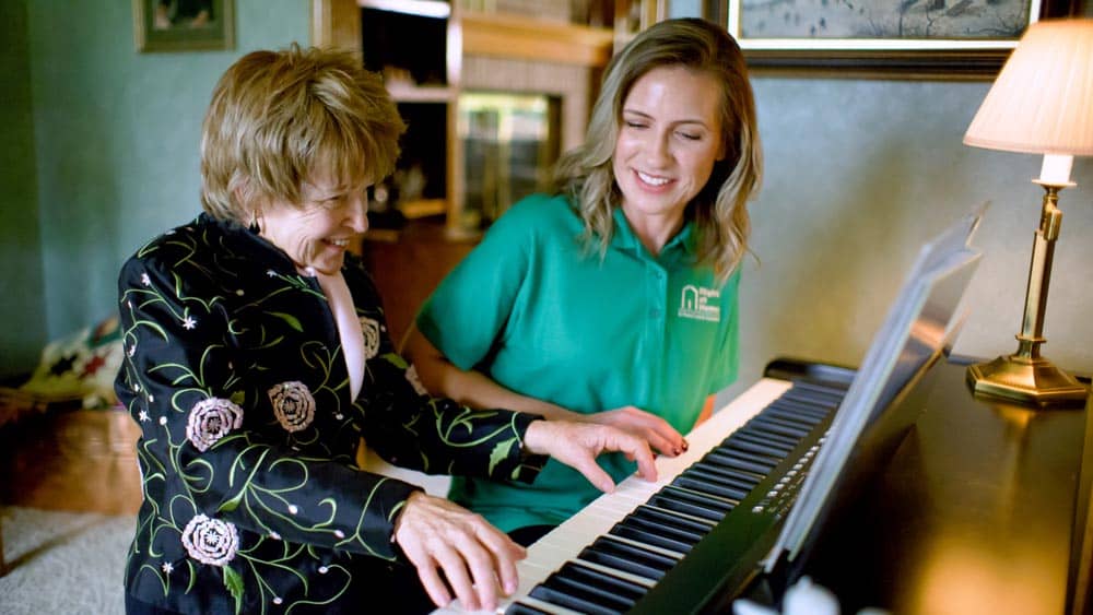 senior playing piano with caregiver 