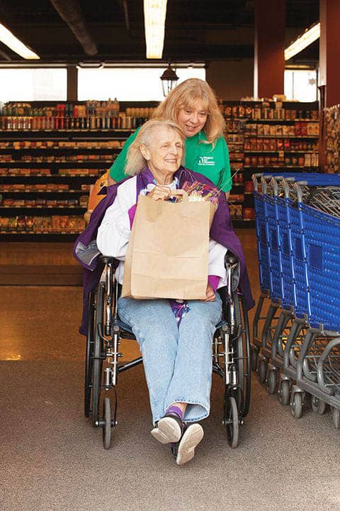 Grocery shopping, caregiver pushing senior in wheelchair