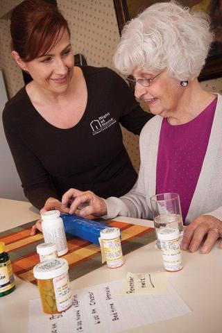 Right at Home Caregiver Standing With Female Senior Client Checking Medications