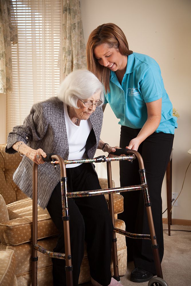 Transition Care, helping senior client stand with walker after surgery