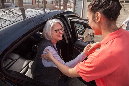 senior transportation caregiver helping senior get out of car