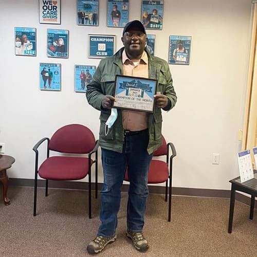 David B., Right at Home Boston Metro West Caregiver of the Month for January of 2021 holding his certificate in the office