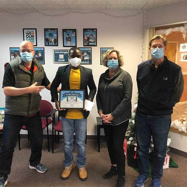 Right at Home Boston Metro West office staff standing with the Caregiver of the Month for Dec. 2020, Ibrahim M. holding his award certificate