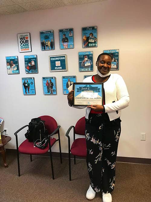 Sarah K., Caregiver of the Month for February 2021 for Right at Home of Boston Metro West holding her certificate in the office