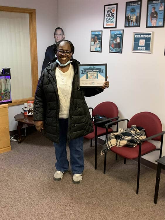 Right at Home of Boston Metro West's Caregiver of the Month for November 2020, Yvonne J. holding her award in the office