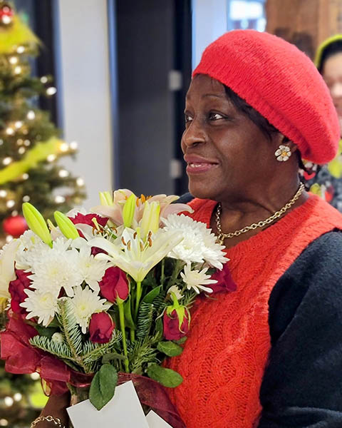 Caregiver Monica smiles while holding flowers