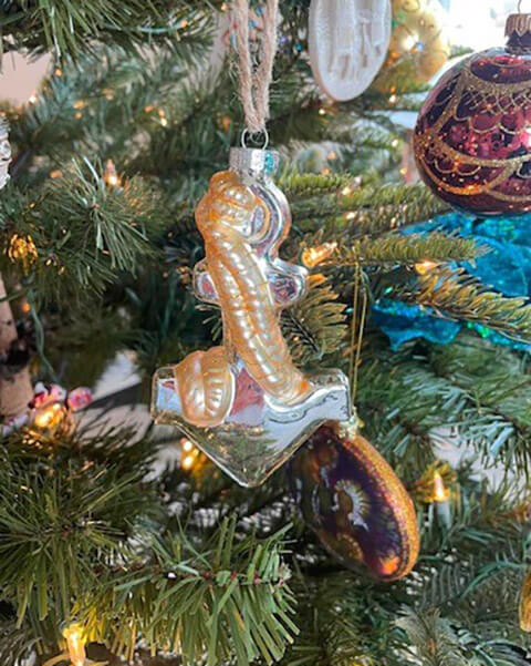 A close-up of an anchor ornament hanging on a Christmas tree.