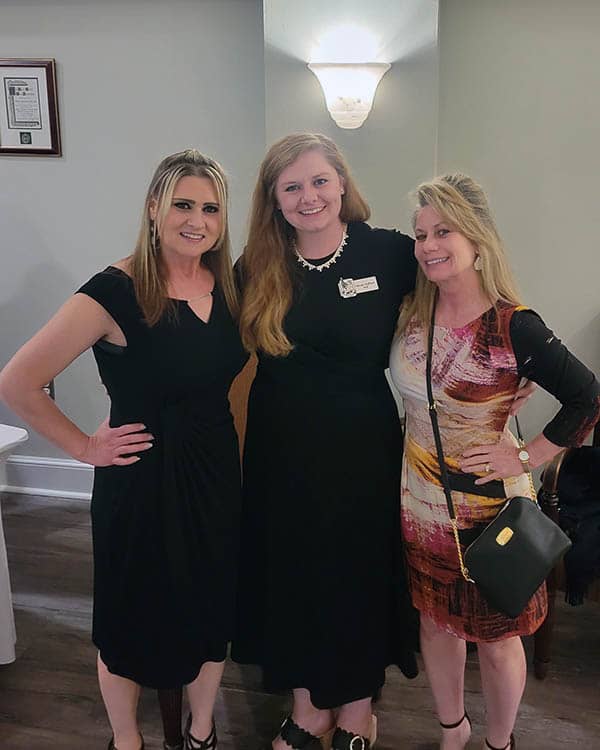 Three females standing side by side in a room dressed in semi-formal attire for the CCVIP Gala.