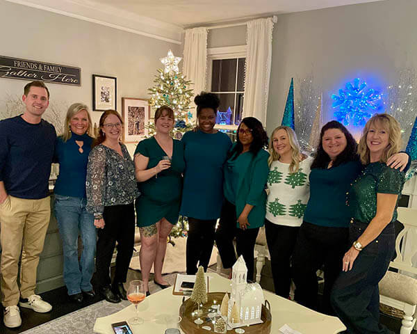 The Howard County staff stand together in a living room with a Christmas tree in the background.