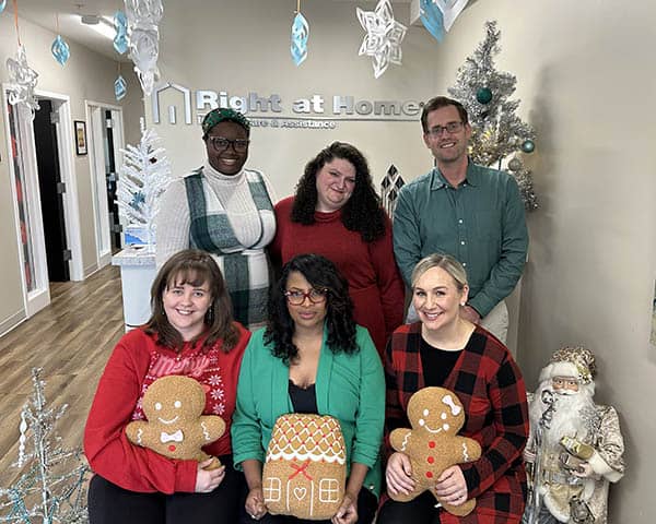 5 women & 1 man pose in an office setting  decorated with snow flakes.