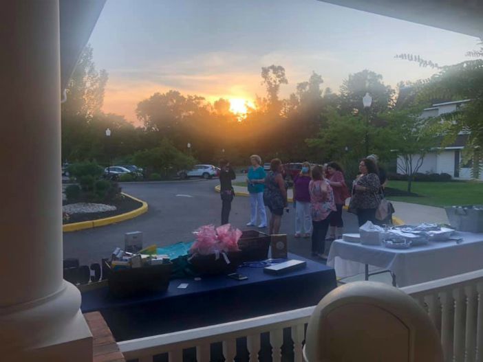 a group of people talking outside of the event while the sun is setting