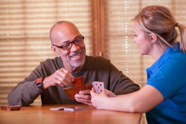 Senior man playing cards with a younger female