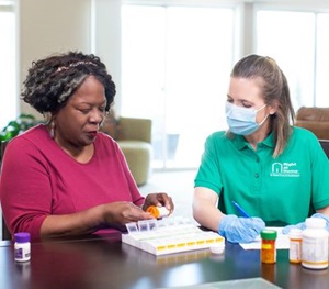 Female caregiver helping plan and distribute medications for the week with a female senior at a table