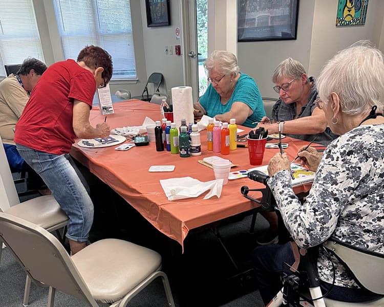 Five senior women sitting around a table doing crafts.