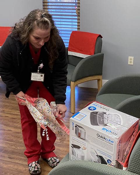 Caregiver Amanda bends over to tear wrapping paper from a box.