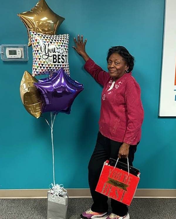 Caregiver Marilyn Carter posing with her retirement balloons and gifts.