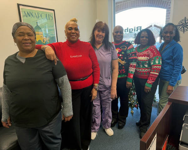 Two staff members stand with a group of female caregivers.