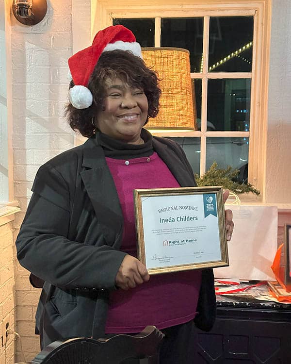 Ineda stands holding her Caregiver of the Year certificate.