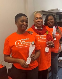 Three female caregivers wearing bright orange Right at Home t-shirts and holding roses.