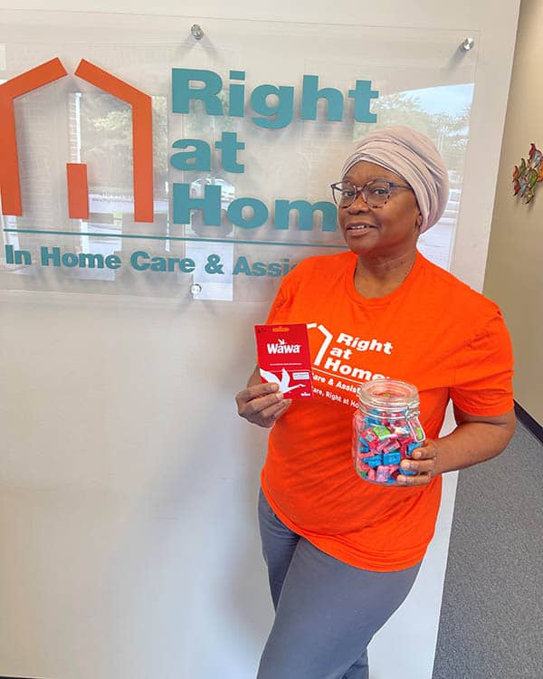 Caregiver, Gigi, holds a jar of candy and the gift card she won.