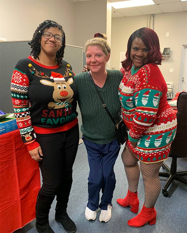 Caregiver and staff donning festive Christmas sweaters