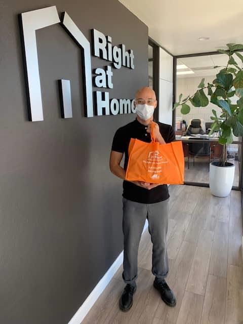 Erik holding orange Right at Home bag with service packets to deliver to Chapman Woods residents