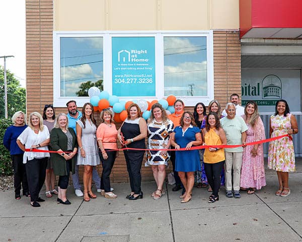 Right at Home owner, April, and community members getting ready to cut the ribbon.