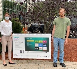 Two Right at Home Southern New Hampshire Caregivers holding a wide screen tv prize outside