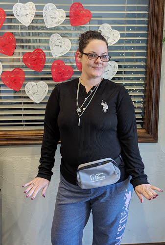 Caregiver Standing in Front of Window Full of Handwritten Hearts During Caregiver Appreciation Week