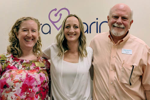 Two women and one man pose side-by-side for a photo as hosts of the Elara Caring Event.