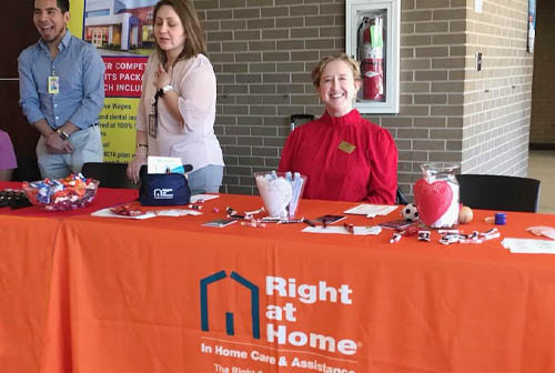 Female Right at Home Staff Member Sitting at a Job Fair Display Table