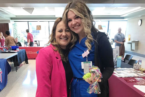 Two Female Staff Members Posing Side-by-Side at Job Fair