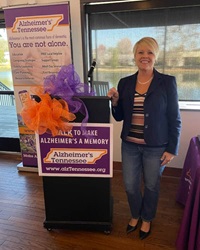 Pam Barnes standing next to a podium at an Alzheimer's Tennessee event.