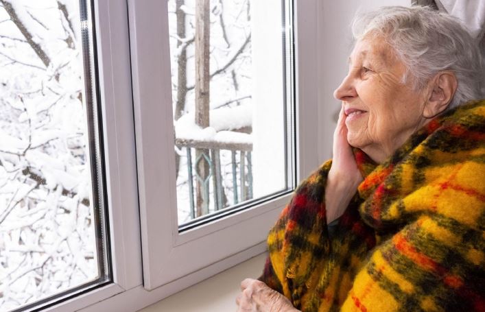 elderly-woman-staring-out-window-and-smiling