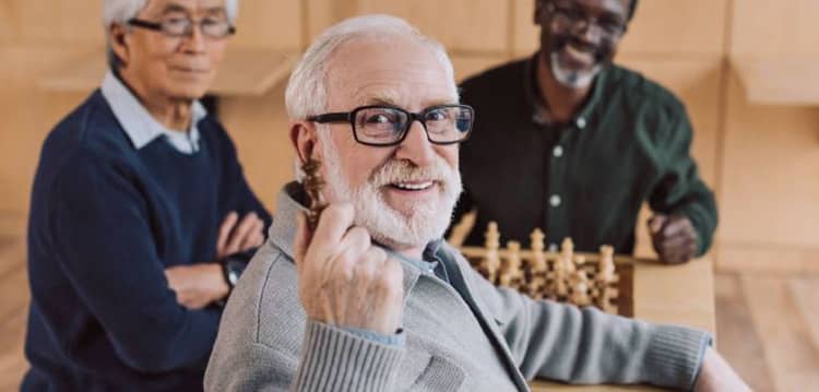 elderly-man-holding-up-a-chess-piece