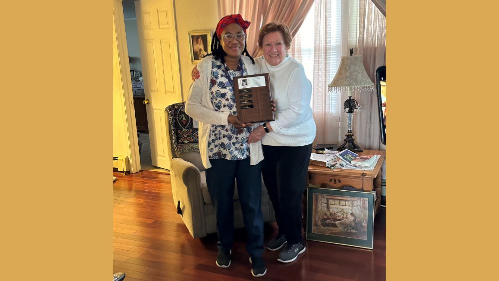 African American woman standing next to a white woman both holding a plaque