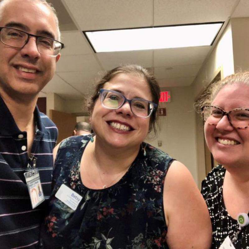  Three individuals smiling and posing together for a cheerful photograph.