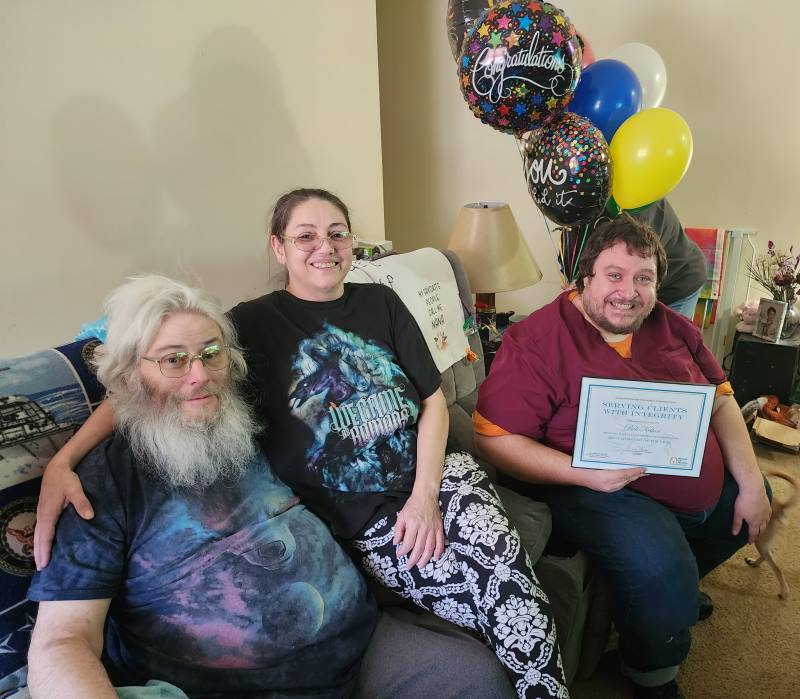 Bob Nelson on end of couch sitting in front of balloons