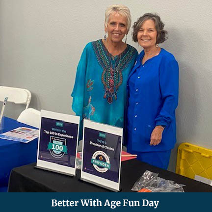 Two Women Posing Side-by-Side Behind a Table with Signs