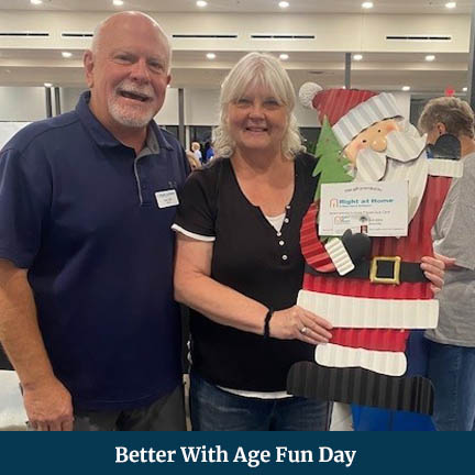 A Man and a Woman Posing Side-by-Side with the Woman Holding a Santa Cut-out