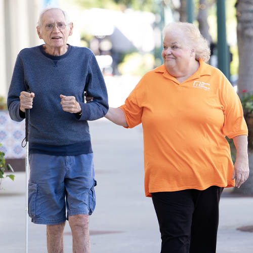Female Caregiver Out for a Walk With Blind Senior Man
